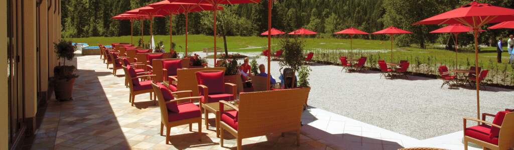 Titelbild Gutjahr Terrasse Terrasse mit roten Schirmen und einer Berglandschaft im Hintergrund