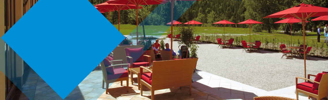 Titelbild Gutjahr Terrasse Terrasse mit roten Schirmen und einer Berglandschaft im Hintergrund